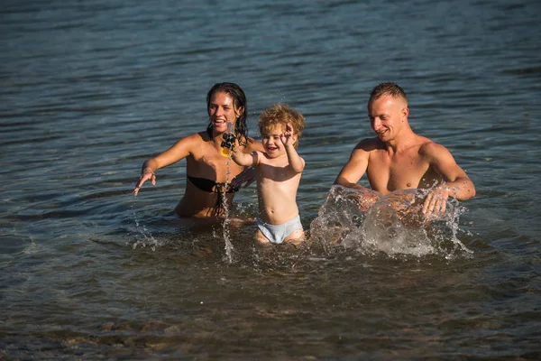 El amor y la confianza como valores familiares. amor de la familia feliz jugando en el agua de mar en la puesta del sol . — Foto de Stock