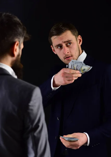 Businessman holds bunch of dollars. Guy pays with cash money. Financial deal between businessmen, black background. Purchase concept. Men in formal suits meet for business deal — Stock Photo, Image
