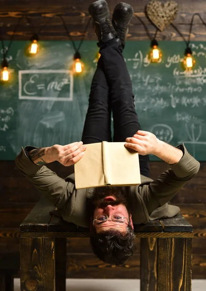 Un hombre con barba larga leyó un libro en el escritorio de la escuela. Hombre leer libro sobre la mesa en clase o biblioteca, bibliopole —  Fotos de Stock