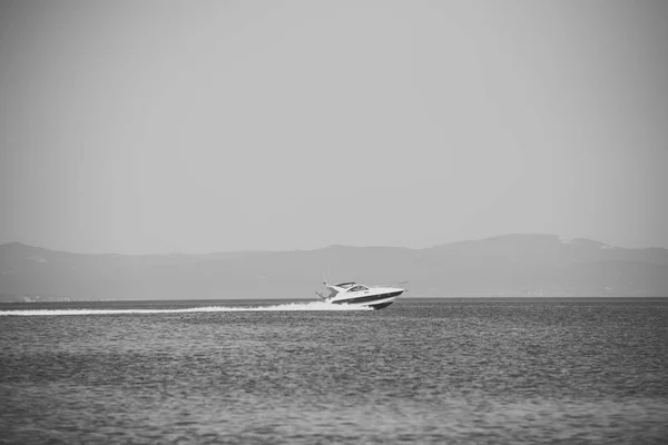 Speed boat. High speed boat in sea, blue sky and mountains on background. Amazing view on white luxury yacht glides on sea surface. — Stock Photo, Image