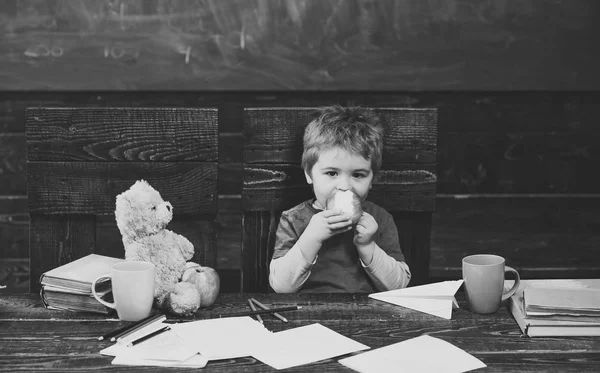 School pauze. Hongerig kind eten apple in de klas. Kleine jongen spelen met papier vliegtuig — Stockfoto