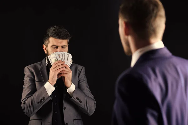 Business succsses. Man with beard on calm face sniffing money, smell of profit. Meeting of reputable businessmen, black background. Business payment concept. Businessmen, business partners counting — Stock Photo, Image