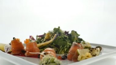 Lezzetli kırmızı balık veya plaka üzerinde bulanık renkli arka plan üzerinde jöle turuncu havyar ve yeşil salata karışımı ile Somon rulo. Modern moleküler Gastronomi.