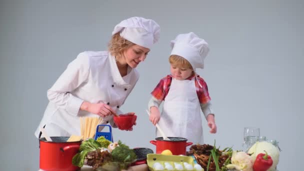 Carino il bambino e la sua bella madre sorridente mentre cucinava in cucina. Infanzia Bambini Felicità Concetto. Giovane cucina familiare in cucina. Giovane madre e figlio cucinare pasto insieme . — Video Stock