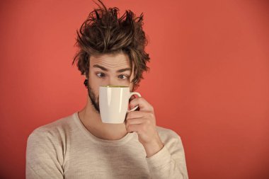 Sabah kahve veya süt. Çay bardağı kırmızı zemin üzerine şaşırmış adam. Soğuk algınlığı ve grip, tek. Dağınık saçlı adam mulled şarap iç. Uykusuzluk, ferahlık ve enerji.