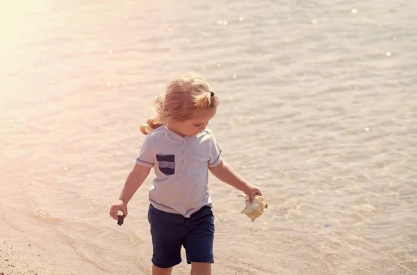 子供休日。海のビーチでシェルを持つ少年 — ストック写真