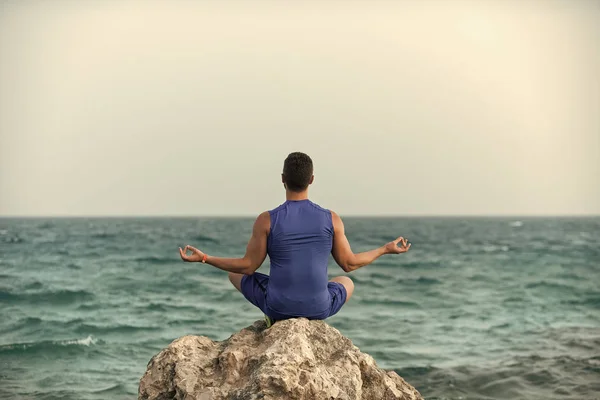 Cuidado de la salud. Hombre practicando yoga cerca del océano azul —  Fotos de Stock