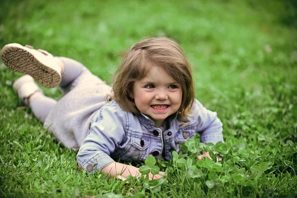 Kid lägger på gräs. Barnet ler på grönt gräs — Stockfoto