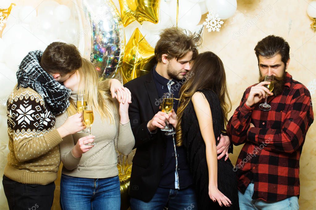 Women and men enjoy party celebration. Friends celebrate christmas or new year. Men and women drink champagne. Couples of lovers kiss, relations. Christmas and new year holidays