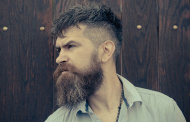 Sakallı adam ahşap arka plan üzerinde. Uzun Sakal ve bıyık tıraşsız yüzündeki olan adam. Şık saç ile moda hippi. Berber ve Kuaför Salonu. Cilt Bakımı ve saç bakımı