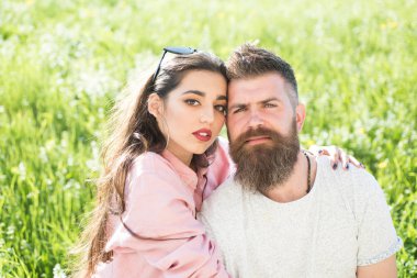 Sakal ve kadın oturur bahar günü çimenlerin üzerinde olan adam. Bahar eğlence kavramı. Aşık çift zaman açık havada ve hugs harcamak. Çayır, Doğa arka plan üzerinde oturan mutlu rüya gibi yüzler üzerinde çift