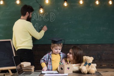 Çocuk Anne dikkat dinliyor. Evde eğitim kavramı. Aile hakkında akıllı küçük oğulları eğitim veriyor. Kara tahta arka plan baba yazar iken zeki oğlu, annesi öğretir