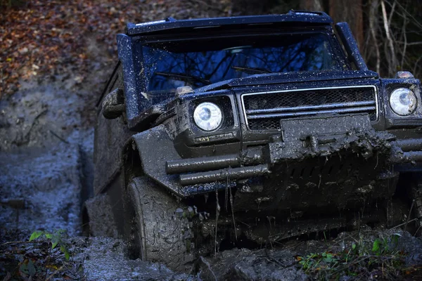 SUV covered with mud stuck in deep puddle. — Stock Photo, Image