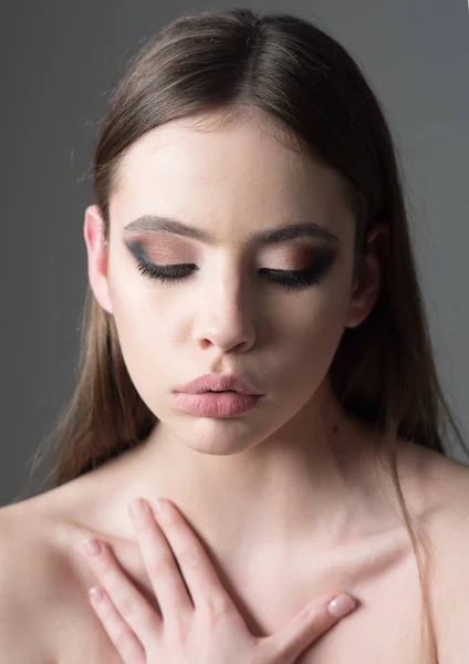 Makeup smokey eyes for model with soft skin. Fashion look concept. Beauty and hairdresser. Girl with pale face on grey background. Trendy woman with stylish hair and fashionable makeup.