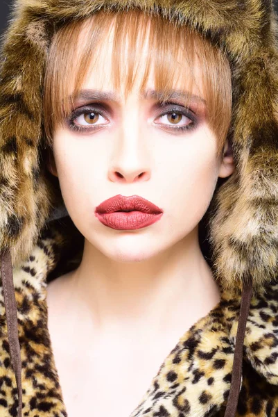 Portrait of wonderful woman looking at camera. girl in leopard fur coat and hat