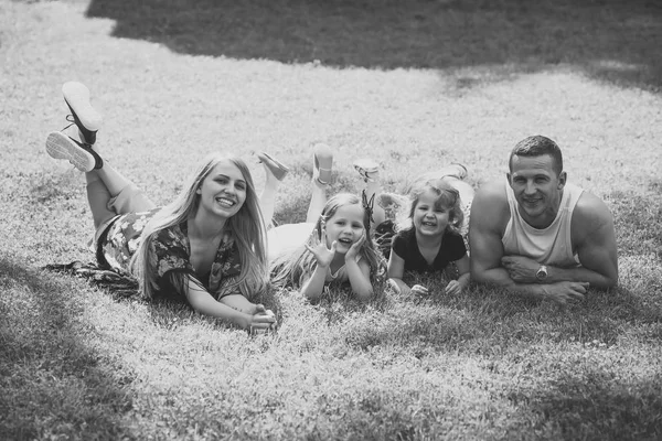 Children and parents lie on green grass — Stock Photo, Image