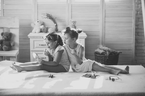 Les enfants sourient et s'assoient au lit avec du rouge à lèvres, du vernis à ongles et un miroir — Photo