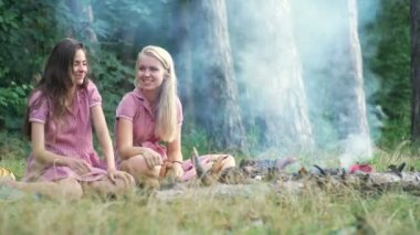 PIN günbatımında bir piknik Park eğlenmek tarzında iki genç kadın. Yaz, tatil, tatil, mutlu insanlar kavramı - kız gülümsüyor. Piknik üzerindeki Girlfriends.