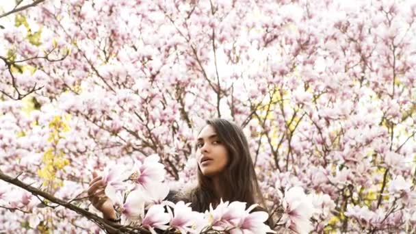 Genç güzel mutlu gülümseyen Bayan çiçekli ağacın yanında poz — Stok video
