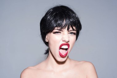 Siyah peruk Bayan gri arka plan üzerinde olun. Skandal kadın kavramı. Kız çıplak omuz ile poz skandal bağırarak yüzünde. Kadın çekici kırmızı dudaklar ile kameraya görünüyor