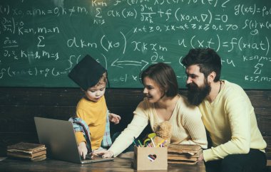 Modern eğitim kavramı. Lisansüstü şapkalı akıllı çocuk eğitim seviyor. Dizüstü bilgisayar kullanmak çocuk öğretim anne. Çocuk Anne ve baba için onun bilgi sunma. Anne oğlu, arka plan kara tahta öğretir.