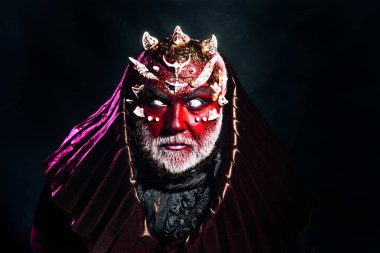 İblis dikenler metalik kaputu giyen kırmızı deri ile. Şeytan kör gözleri siyah arka plan üzerinde cehennem izole ve terör kavramı