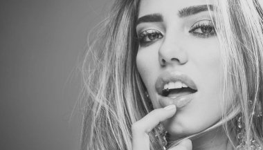 Kadın kopya alanı dudaklar görünüyor çekici, çok dokunaklı. Güzellik makyaj, ruj, göz farı, maskara, seksi kız moda büyük küpeler takı, gri studio arka plan giyer. Profesyonel makyaj kavramı.