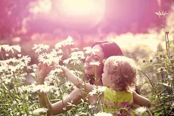Žena a dítě úsměv na slunný květinový krajiny — Stock fotografie