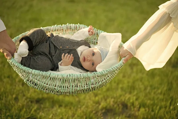 Péče o děti. Novorozenec leží v postýlce držel v rukou na zelené trávě — Stock fotografie