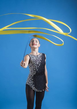 Eğitim ve egzersiz kavramı. Eğitim ve egzersiz bir jimnastikçi kız şerit üzerinde mavi arka plan ile.