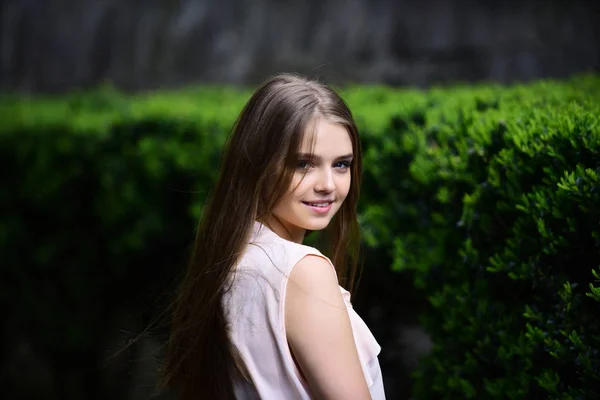 Femme sexy aux cheveux longs dans un parc d'été. regard de fille près des plantes vertes. fille en vêtements décontractés en plein air. Mode et beauté d'été ou de printemps. modèle sensuel avec maquillage après coiffeur — Photo