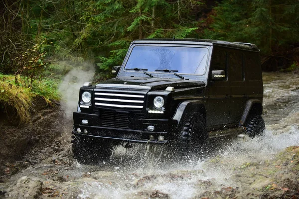 Voiture 4x4 ou hors route en couleur noire traversant le cours d'eau Voiture de course avec ruisseau sur le chemin. Course hors route en forêt Conduite extrême, défi et concept de véhicule 4x4 — Photo