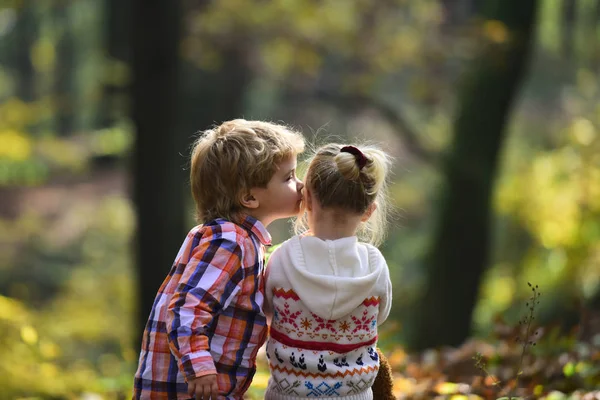 Menino beijo menina pequena amigo na floresta de outono. Irmão beijar irmã com amor na floresta. Conceito do dia dos namorados. Amor de família e confiança. Amizade infantil e crianças desenvolvimento precoce — Fotografia de Stock