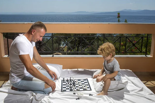 Smart concept tout-petit Papa avec enfant jouer jeu intellectuel Père et petit fils jouer aux échecs sur le balcon nature et mer sur fond — Photo