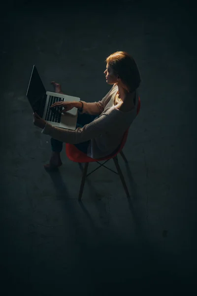 Vista dall'alto della giovane donna seduta sulla sedia con computer portatile . — Foto Stock