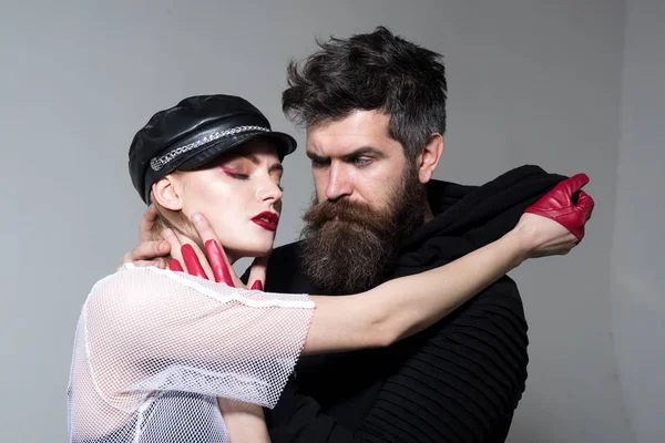 hippi kız deri şapka ve eldiven ve sakal ile. iki seksi kadın ve sakallı adam aşık. Rock çift gri arka plan üzerinde kucaklıyorum. dostluk ve sevgi kavramı. rock tarzı ve moda trend.