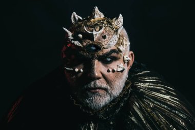 Uzaylı, iblis büyücü makyaj. Üçüncü göz, dikenler veya siğiller olan adam. Siyah arka plan, kopya alanı cehennemdeki şeytanlar. Korku ve hayal kavramı. Beyaz sakallı komuta sizde karanlıkta canavar gibi giyinmiş