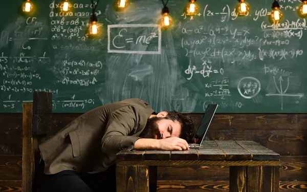 Guapo barbudo chico siesta cerca de la computadora portátil mientras trabaja duro en la oficina de la escuela —  Fotos de Stock