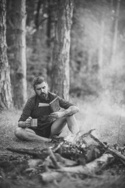 kamp. Adam gezgin okumak ve kamp ateşi alev içki