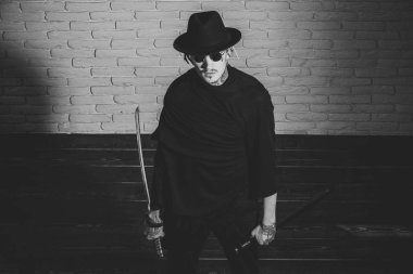 bir kılıç ile acımasız dövmeli adam. Savaşçı siyah güneş gözlüğü, şapka ve kıyafet, üstten görünüm