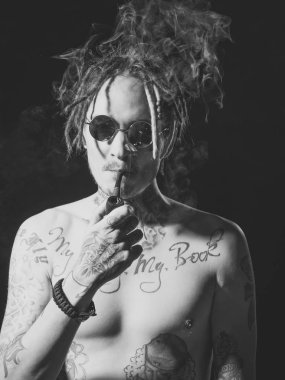 acımasız dövmeli adam pipo içiyor. Adam hippi yasaktır boru siyah arka plan üzerine