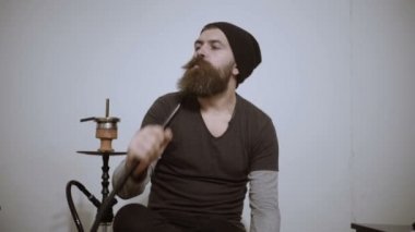 Genç adam nargile içiyor ve duman halkaları sağlar