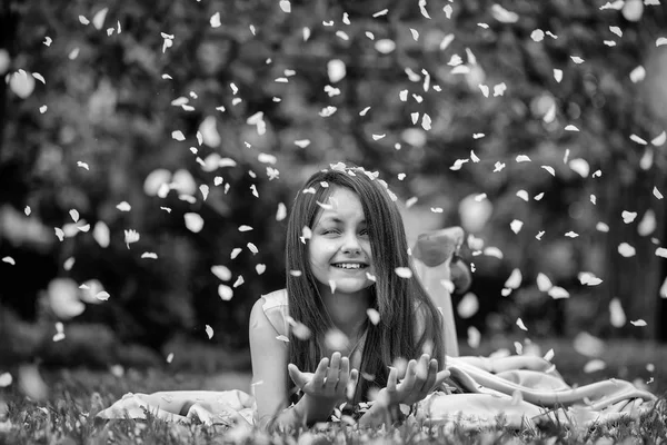 Šťastné dítě a květinové lístky. Malá holčička na zelené trávě s lístky — Stock fotografie