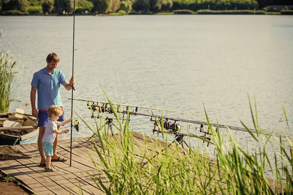Снасти для рыбалки Мужчина и мальчик рыбачат на удочках с деревянного пирса — стоковое фото