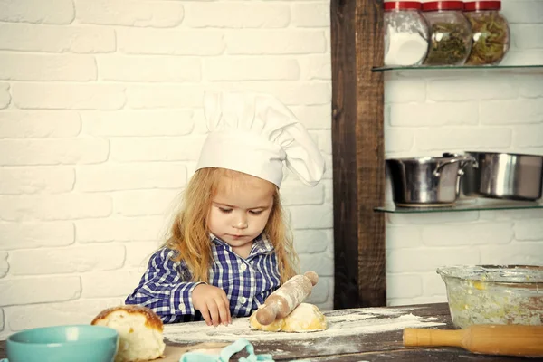 Die junge Köchin. das Konzept des zukünftigen Berufs. Kind kocht in Kochmütze Teig rollen mit Holznadel — Stockfoto