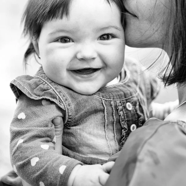 Bambino sorridente tra le braccia della madre. Bella bambina. — Foto Stock