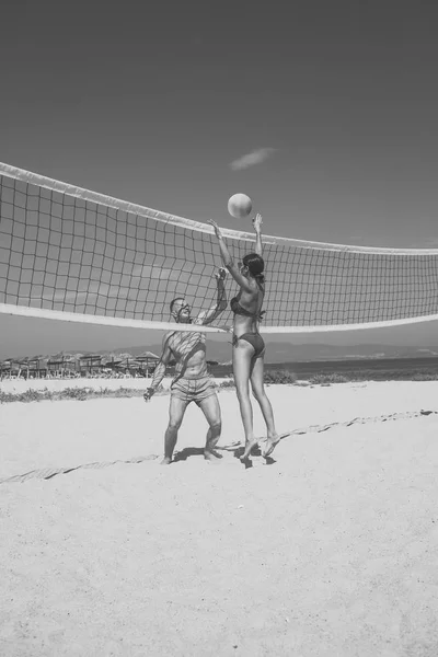 ビーチバレー。スポーティなアクティブなカップルは、連発の球を撃退、夏の日のゲームをプレイします。女と男フィット、強く、健康なビーチでスポーツを行います。ビーチ バレーボール コンセプト。カップルが楽しくプレー — ストック写真