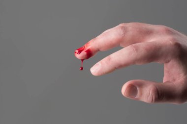 Eli yaralı kanlı orta parmak gri arka plan, kopya alanı ile. Zarar ve yaralanma kavramı. Damlacık aşağı düşen kan. Kan ve ilk tıbbi yardım kaybı