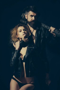 Rock and roll kavramı. Sakal ve seksi kız sutyen ile gitarist rock and roll yaşam tarzı tadını çıkarın. Çift seksi ve vahşi gitar ile poz. Çift gitar, siyah arka plan ile sarılma aşık