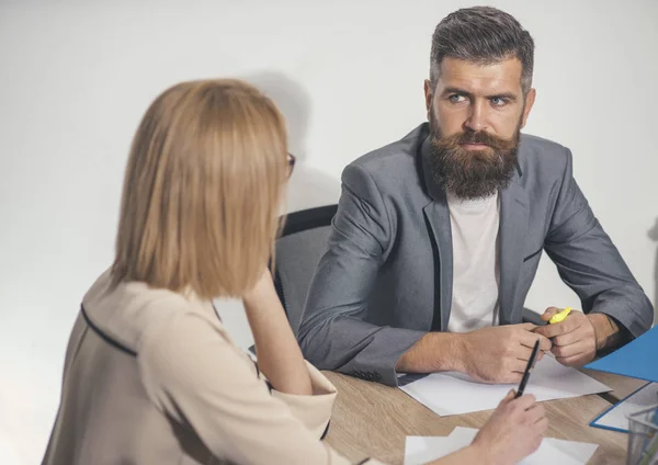 Uomo barbuto seduto alla scrivania con donna, vista posteriore. Un uomo d'affari lavora al business plan con una donna d'affari. Uomo con la barba e i baffi sul viso serio. Concetto di riunione d'affari. Giornata impegnativa in ufficio — Foto Stock